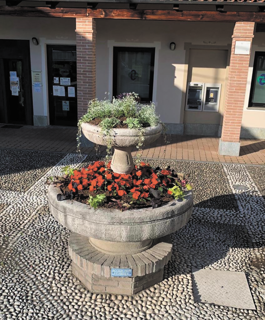 Fiori abbelliscono la fontana nella piazzetta di Osasio